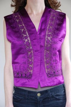 Gianni Versace 1990's silk satin fancy cut out lace vest. Super cool paired with your favorite high waisted jeans in a boho rock star look or maybe more party Euro trash with a black leather pencil skirt. Super shiny luminous royal purple color!Beautiful embroidery with elaborate lace cutouts bordering the hem. One button at front that can be closed or left open if you wish. Fully lined. Label Gianni Versace, Made in Italy. 100% silk, dry clean only. Size 42. Good vintage condition - to note is Fitted Vintage V-neck Vest, Fitted Silk Summer Vest, Formal Silk Vest For Spring, Vintage Party Vest For Spring, Vintage Spring Party Vest, Spring Party Vintage Vest, Vintage Fitted Party Vest, Fitted V-neck Vintage Vest, Versace 1990's