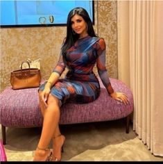 a woman sitting on top of a pink couch next to a handbag and purse