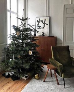 a small christmas tree sitting in the corner of a room next to a green chair