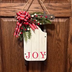 a christmas door hanger with a joy sign hanging from it's front door