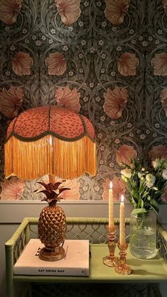 a table with two vases and candles on it in front of a wallpapered background