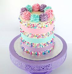 there is a multi layer cake on top of a purple stand with sprinkles