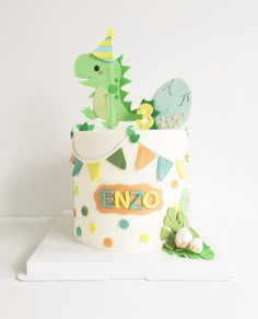 a birthday cake that is decorated like a dinosaur and has decorations on the top tier