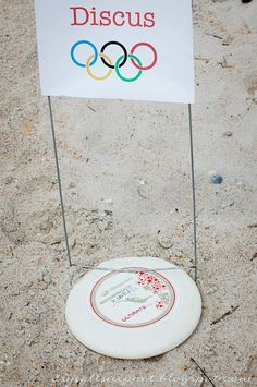 a white frisbee sitting in the sand next to a sign that says discuss