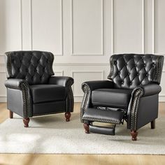 two black leather chairs sitting next to each other on a white rug in front of a wall