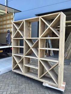 a large wooden bookcase sitting on top of a brick floor next to a building