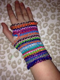 a child's hand wearing a multicolored knitted arm warmer