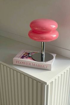 a pink lamp sitting on top of a book next to a white radiator