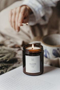 a person lighting a candle on top of a book