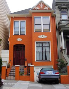 a car parked in front of an orange two story house with white trim and windows