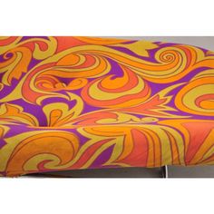 an orange and purple chair with swirly fabric on the backrest, in front of a gray background