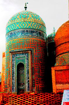 an ornate building with blue and green tiles on it's sides, surrounded by brick walls