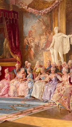 a large group of people in fancy dresses sitting on the floor next to a statue