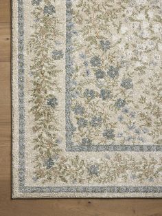 an area rug with blue and green flowers on the side, sitting on top of a wooden floor