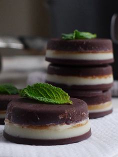 three chocolate desserts are stacked on top of each other, with mint sprigs