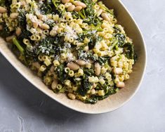 a bowl filled with pasta and broccoli covered in parmesan cheese