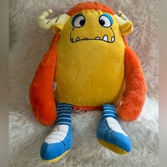 a yellow stuffed animal sitting on top of a white blanket with blue and orange socks