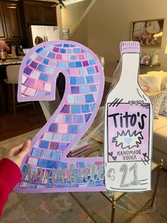 a paper cut out of the number two with a bottle in front of it on a table