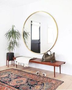 a room with a rug, mirror and plant in it