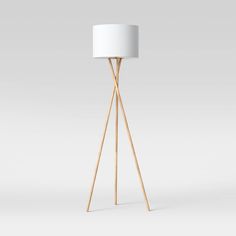 a wooden tripod floor lamp with a white shade on it's top and bottom