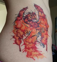 a woman's lower back tattoo with an orange and red design on her stomach