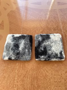 two square pieces of felt sitting on top of a wooden table next to each other