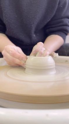 a person working on a pottery wheel with their hands