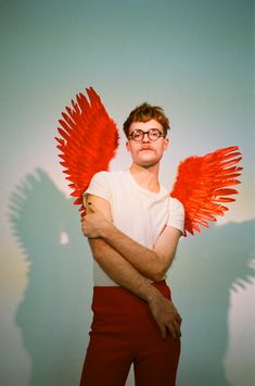 a man with red wings standing in front of a wall