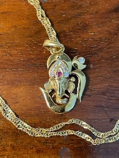 Beautiful and Intriquing 18K Yellow Gold Ruby and Diamond Om Ganesh Pendant Necklace is a rare opportunity to add to someone's jewelry collection.  Om Ganesh, the elephant headed Hindu God of prosperity and wisdom, is magnificently portrayed in this creation.  The pendant weighs 2.1 grams displaying a ruby (1.3mm) and eight diamonds (four 1mm and four 1.3mm).  The pendant is not marked, but tests for 18k gold.  The sparkling 18K Yellow Gold 17 inch twisted chain necklace is hallmarked 750 (18k) Spiritual Yellow Gold Jewelry For Festive Occasions, Ceremonial Spiritual Yellow Gold Temple Necklace, Yellow Gold Temple Necklace With 17 Jewels For Diwali, Spiritual Yellow Gold Necklace For Festive Season, Spiritual 22k Gold Necklace With Gemstone, Diwali Yellow Gold Necklace With 17 Jewels, Traditional 14k Stamped Pendant Necklace, Spiritual Formal Jewelry For Festivals, Spiritual Jewelry For Formal Festivals