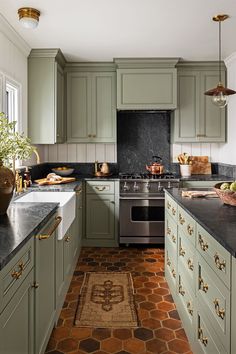 an image of a kitchen setting with green cabinets and black counter tops, including a stove