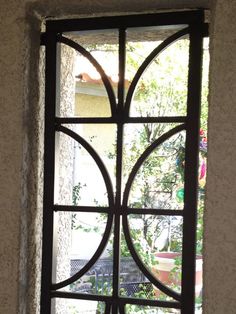 an open window with iron bars on the outside and inside, in front of a white wall