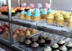 an assortment of cupcakes on display in a bakery