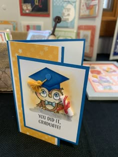 a card with an owl wearing a graduation cap and holding a candy lollipop