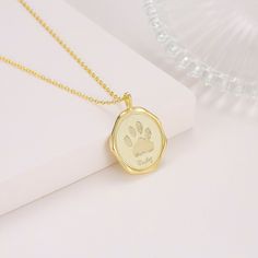 a gold necklace with a dog's paw print on the front and back of it