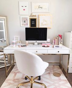 a white desk topped with a computer monitor next to a gold framed wall mounted art