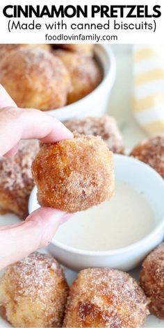 cinnamon pretzels are being held up to the camera with dipping sauce in small white bowls behind them