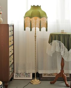 a lamp that is on top of a table next to a dresser and window sill