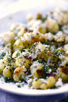 a white plate topped with cauliflower covered in cheese and parmesan sprinkles