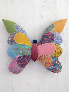 a colorful butterfly hanging on the side of a white wall