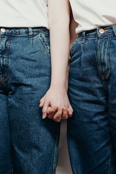 two people standing next to each other with their hands on their hipss, both wearing jeans