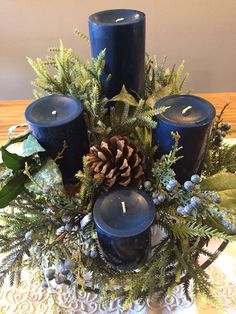 some blue candles are sitting on a table with pine cones and greenery around them