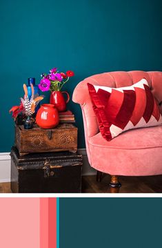 a pink chair sitting in front of a blue wall next to a wooden trunk with flowers on it