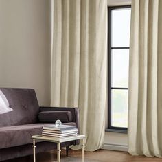 a living room filled with furniture and a window covered in white drapes next to a coffee table