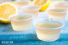 three cups filled with lemonade sitting on top of a blue cloth next to sliced lemons