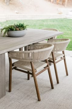 an outdoor table with chairs and a bowl on it's end, in front of a grassy area