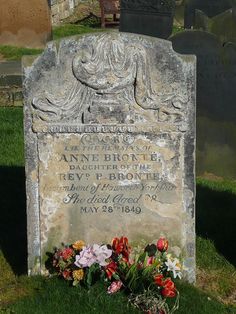 a headstone with flowers in the grass