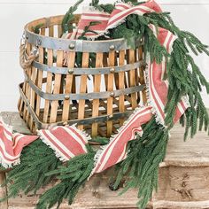 a basket filled with pine branches on top of a wooden table next to a red and white striped blanket