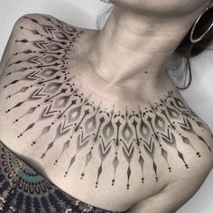 a woman's chest with black and white tattoos on it, including an intricate design