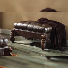 a brown leather bench sitting on top of a hard wood floor next to a window