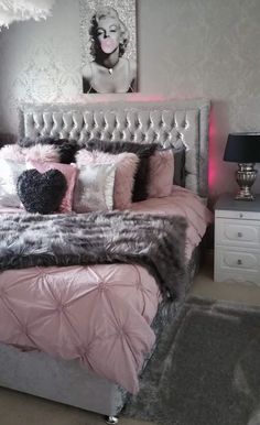 a bedroom with pink and grey bedding, black and white rugs and pictures on the wall